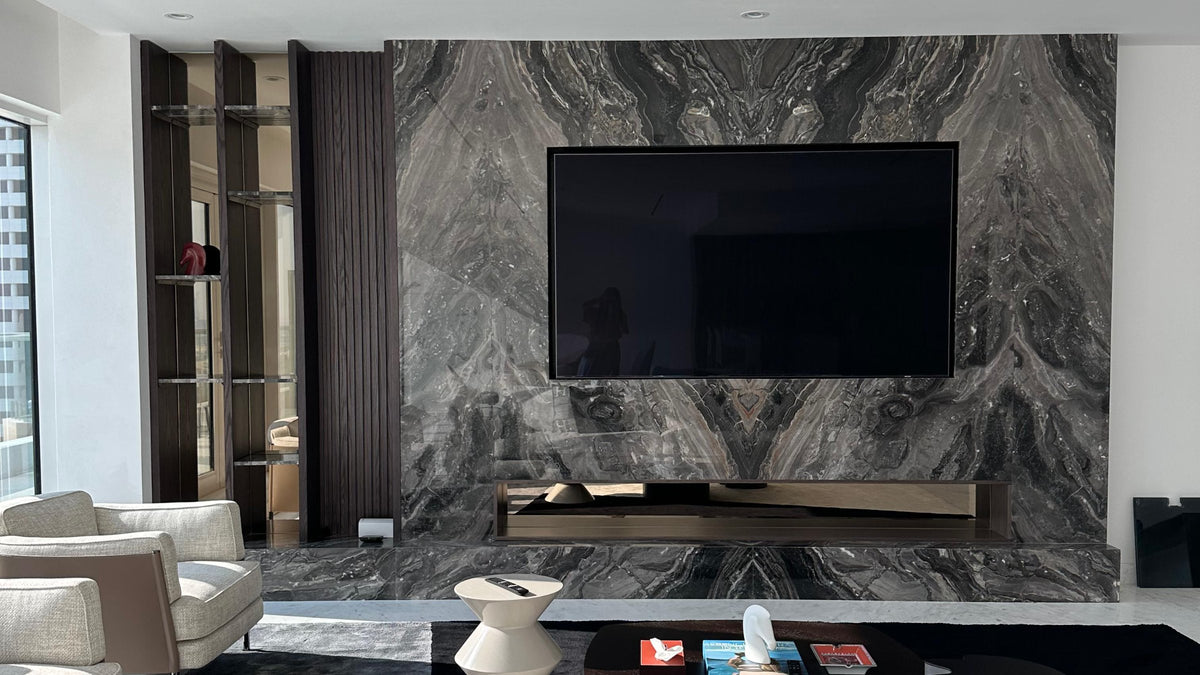 Finished work — a book-matched marble media wall, shot in raking light